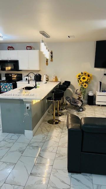 1908 NE 2nd Pl, Cape Coral, FL 33909 - kitchen with black microwave, electric stove, a peninsula, light countertops, and white cabinets
