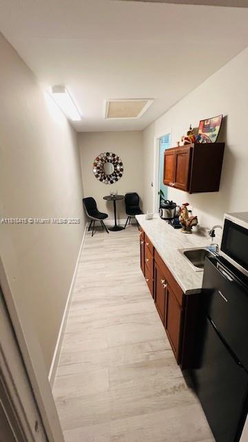 1908 NE 2nd Pl, Cape Coral, FL 33909 - kitchen with light wood-style floors, light countertops, stainless steel microwave, and brown cabinetry