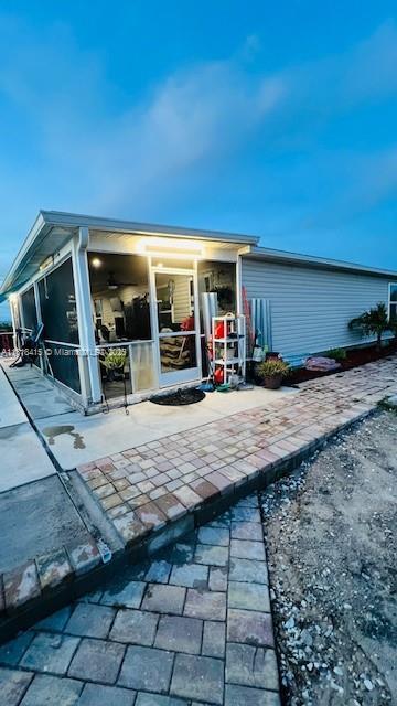 1908 NE 2nd Pl, Cape Coral, FL 33909 - rear view of property with a sunroom, an outdoor pool, and a patio area