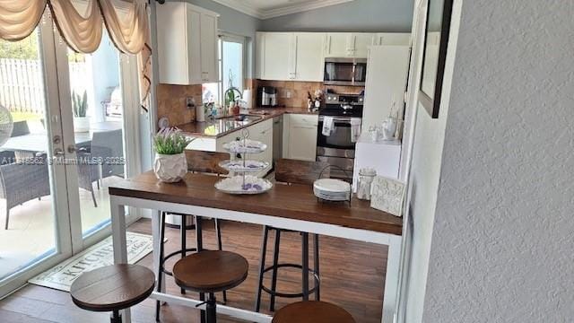9480 NW 10th St, Plantation, FL 33322 - kitchen featuring stainless steel appliances, a textured wall, ornamental molding, white cabinetry, and french doors
