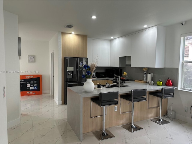 16650 SW 61st Ln, Miami, FL 33193 - kitchen with black fridge with ice dispenser, a peninsula, light marble finish flooring, modern cabinets, and backsplash