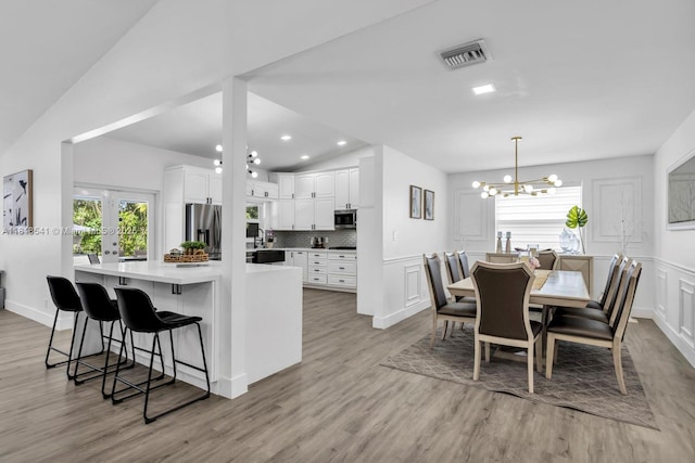 11400 NW 27th St, Plantation, FL 33323 - kitchen featuring stainless steel appliances, white cabinets, lofted ceiling, a chandelier, and light wood finished floors