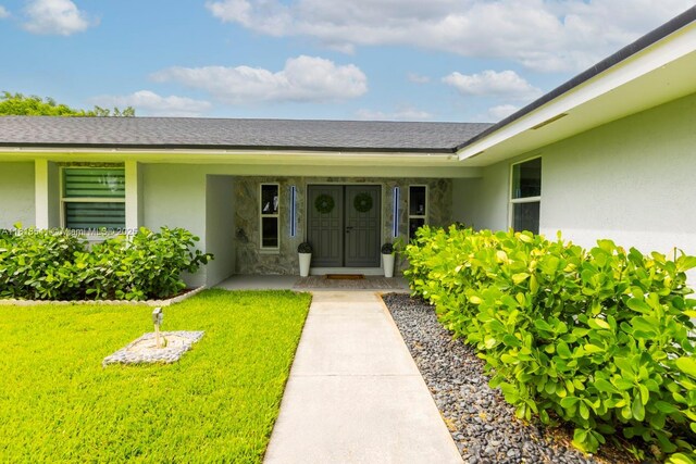 11400 NW 27th St, Plantation, FL 33323 - view of exterior entry with stucco siding, a yard, and covered porch