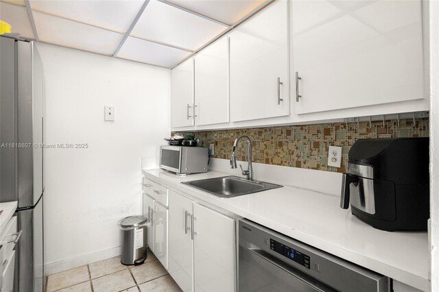 2350 NE 135th St Unit 1006, North Miami, FL 33181 - kitchen featuring appliances with stainless steel finishes, a sink, decorative backsplash, light countertops, and white cabinetry