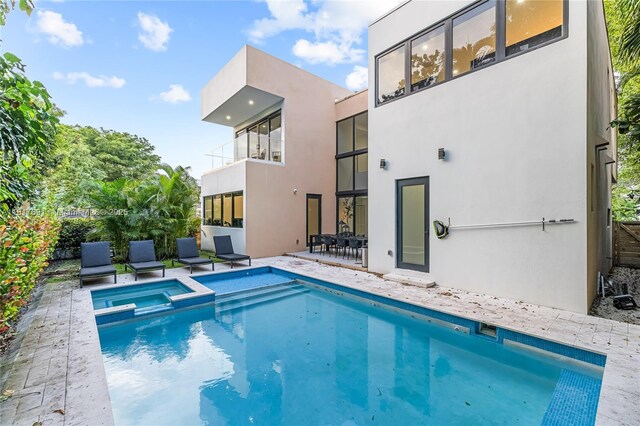 3660 SW 12th St, Miami, FL 33135 - rear view of house featuring a pool with connected hot tub, stucco siding, and a patio
