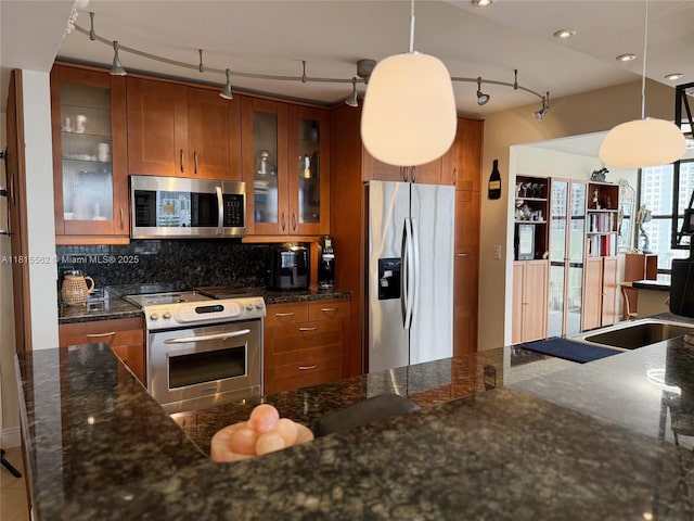 800 Parkview Dr Unit 820, Hallandale Beach, FL 33009 - kitchen featuring appliances with stainless steel finishes, brown cabinets, rail lighting, and backsplash