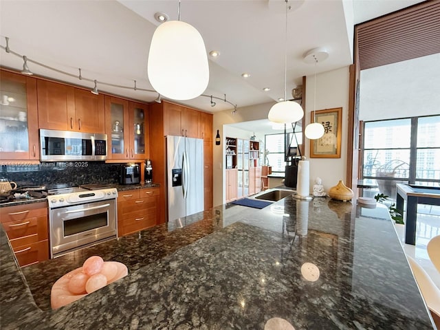 800 Parkview Dr Unit 820, Hallandale Beach, FL 33009 - kitchen with appliances with stainless steel finishes, track lighting, brown cabinets, tasteful backsplash, and hanging light fixtures
