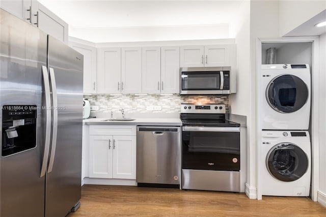 20505 E Country Club Dr Unit 143, Aventura, FL 33180 - kitchen with stainless steel appliances, stacked washer and clothes dryer, decorative backsplash, light wood finished floors, and white cabinets