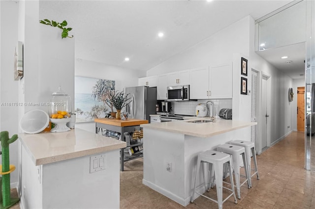 886 SW 180th Ter, Pembroke Pines, FL 33029 - kitchen featuring appliances with stainless steel finishes, a kitchen bar, backsplash, a peninsula, and white cabinetry
