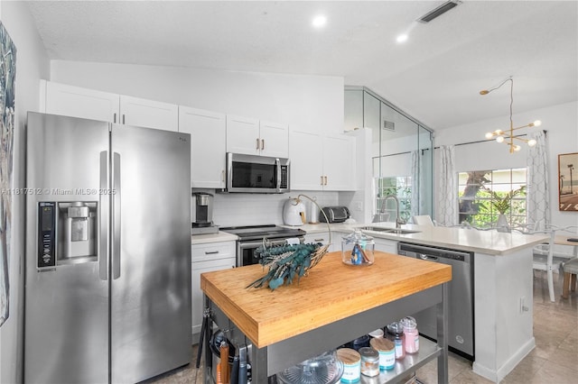 886 SW 180th Ter, Pembroke Pines, FL 33029 - kitchen featuring appliances with stainless steel finishes, lofted ceiling, a peninsula, tasteful backsplash, and white cabinets