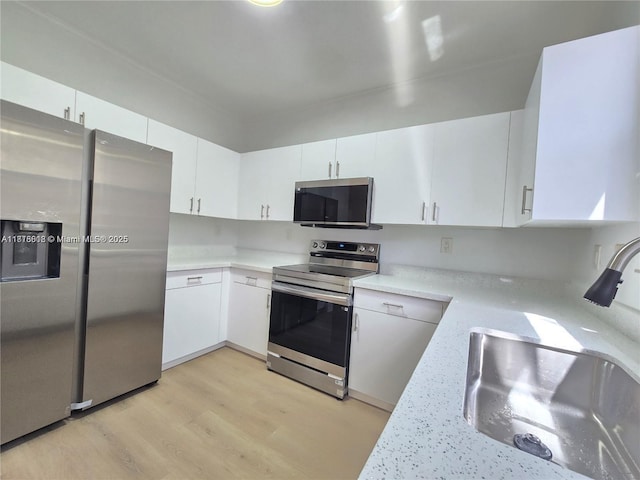 129 Riverwalk Cir Unit 129, Sunrise, FL 33326 - kitchen featuring stainless steel appliances, a sink, light countertops, light wood-style floors, and white cabinetry
