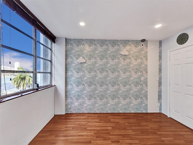 1408 Brickell Bay Dr Unit 411, Miami, FL 33131 - unfurnished room featuring wallpapered walls, plenty of natural light, an accent wall, wood finished floors, and recessed lighting