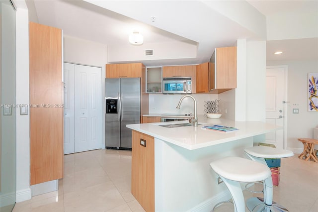 480 NE 30th St Unit 1505, Miami, FL 33137 - kitchen with appliances with stainless steel finishes, a peninsula, a kitchen bar, light countertops, and light tile patterned floors