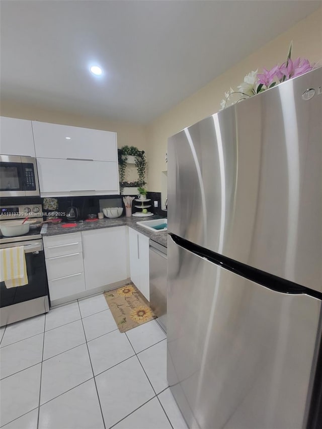 9235 Lagoon Pl Unit 403, Davie, FL 33324 - kitchen featuring stainless steel appliances, white cabinets, dark countertops, light tile patterned floors, and modern cabinets