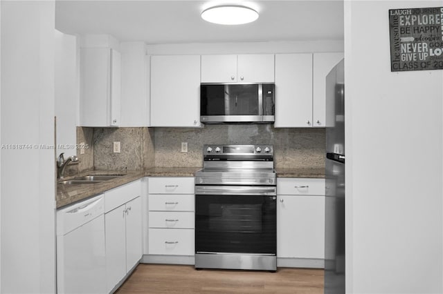 1250 S Miami Ave Unit 2310, Miami, FL 33130 - kitchen featuring appliances with stainless steel finishes, white cabinetry, light wood-type flooring, backsplash, and dark stone countertops