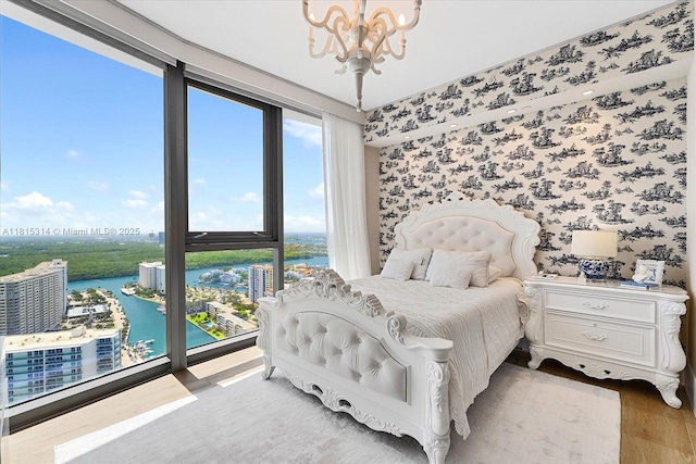15701 Collins Ave Unit 3101, Sunny Isles Beach, FL 33160 - bedroom featuring a chandelier, a water view, wood finished floors, wallpapered walls, and a view of city