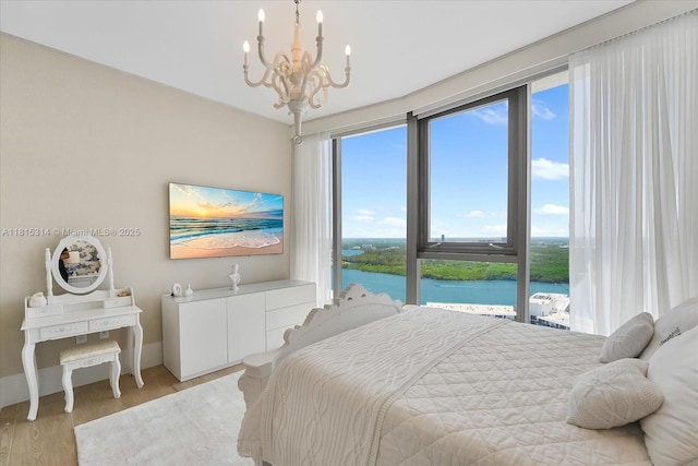 15701 Collins Ave Unit 3101, Sunny Isles Beach, FL 33160 - bedroom featuring a water view, a chandelier, multiple windows, and light wood-type flooring