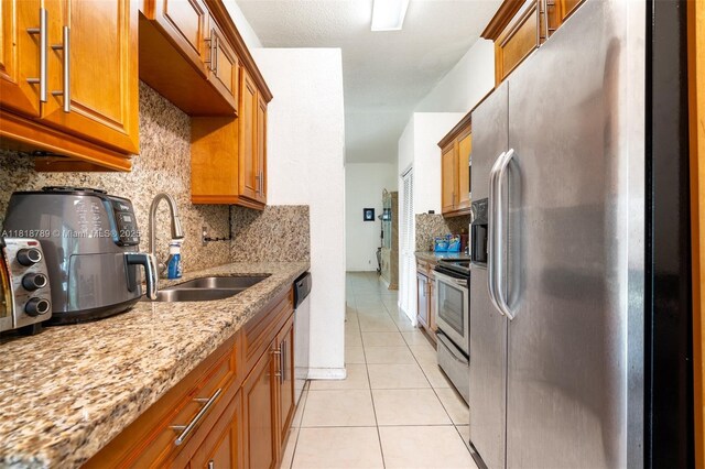 7382 NW 34th St, Lauderhill, FL 33319 - kitchen with appliances with stainless steel finishes, a sink, decorative backsplash, brown cabinetry, and light tile patterned floors