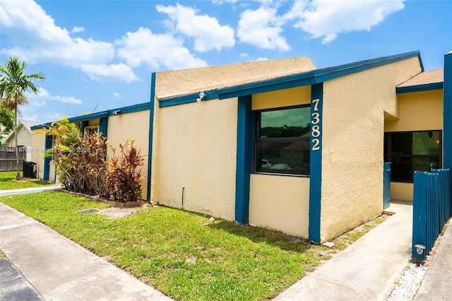 7382 NW 34th St, Lauderhill, FL 33319 - view of property exterior featuring stucco siding, a lawn, and central air condition unit