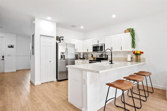 9362 W 33rd Ln, Hialeah, FL 33018 - kitchen with appliances with stainless steel finishes, a peninsula, a kitchen breakfast bar, light wood-style floors, and recessed lighting