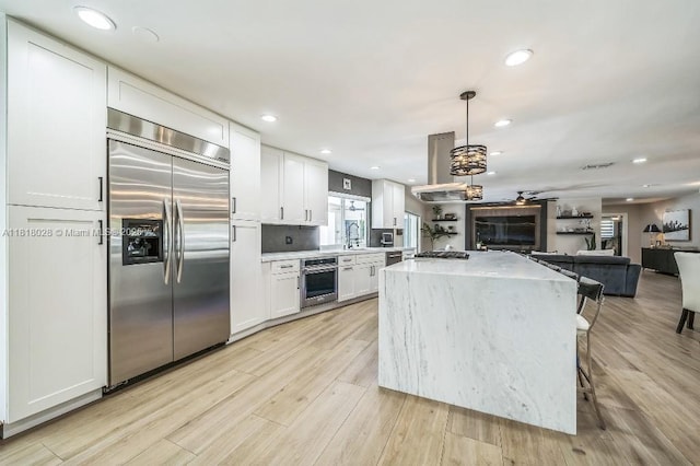 8005 SW 89th St, Miami, FL 33156 - kitchen with appliances with stainless steel finishes, open floor plan, white cabinets, a center island, and light wood finished floors