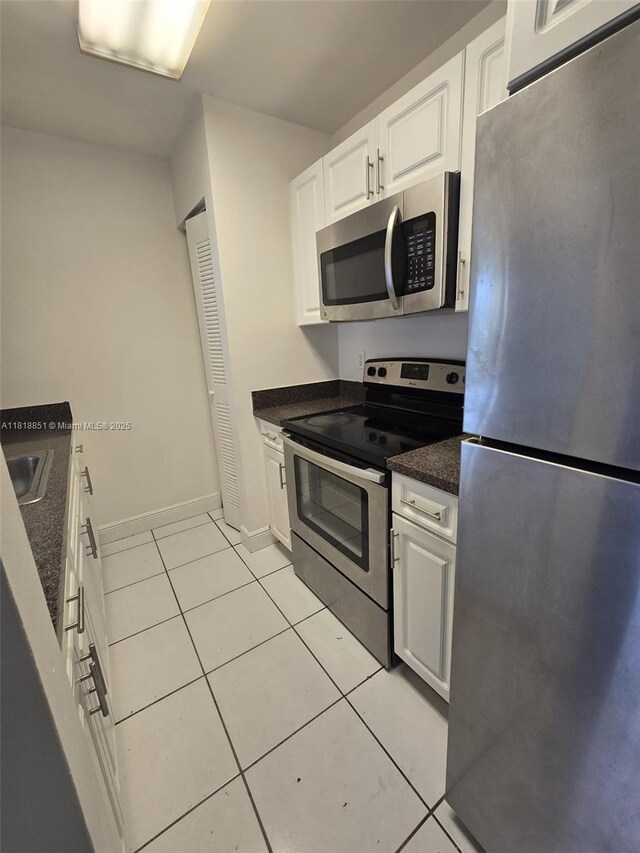 9808 Hammocks Blvd Unit 203-23, Miami, FL 33196 - kitchen with appliances with stainless steel finishes, light tile patterned flooring, white cabinets, baseboards, and dark stone countertops