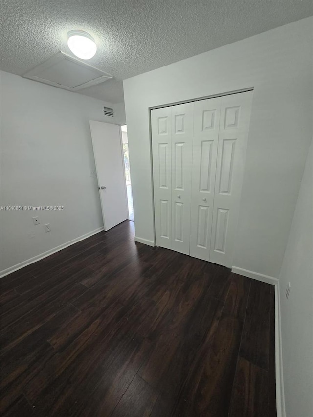 9808 Hammocks Blvd Unit 203-23, Miami, FL 33196 - unfurnished bedroom with attic access, dark wood finished floors, a textured ceiling, a closet, and baseboards