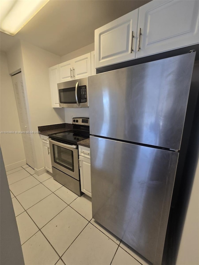 9808 Hammocks Blvd Unit 203-23, Miami, FL 33196 - kitchen featuring appliances with stainless steel finishes, light tile patterned floors, dark countertops, and white cabinetry