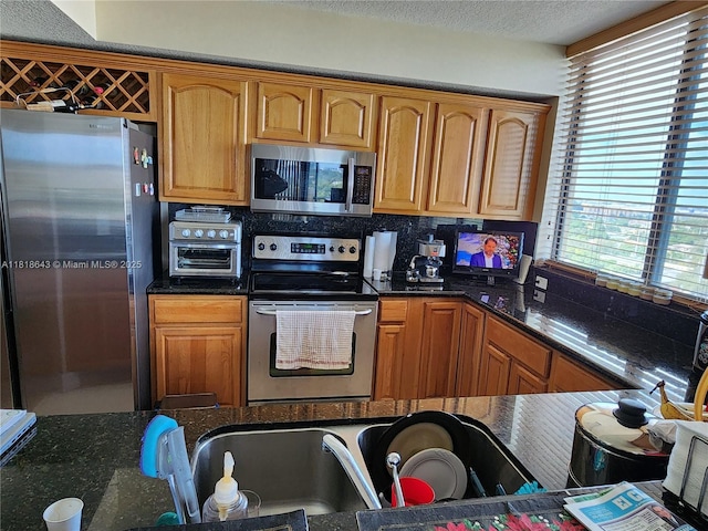 4242 NW 2nd St Unit 1202, Miami, FL 33126 - kitchen featuring stainless steel appliances, dark stone counters, tasteful backsplash, brown cabinets, and a textured ceiling