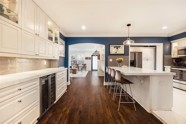 261 SW 30th Rd, Miami, FL 33129 - kitchen with appliances with stainless steel finishes, wine cooler, arched walkways, a kitchen bar, and decorative backsplash