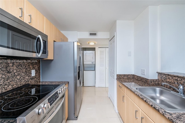 2400 SW 27th Ave Unit 402, Miami, FL 33145 - kitchen with appliances with stainless steel finishes, stacked washer / dryer, light brown cabinets, and light tile patterned flooring