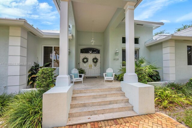 6129 SW 74th Ct, Miami, FL 33143 - view of front facade featuring stucco siding, a standing seam roof, a metal roof, and covered porch