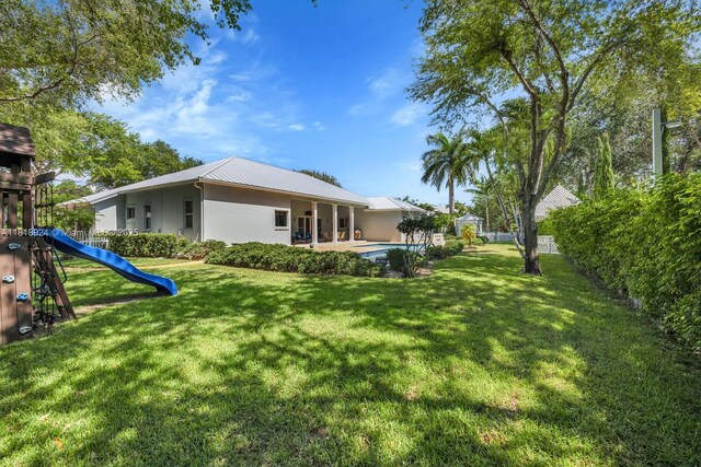 6129 SW 74th Ct, Miami, FL 33143 - back of property with a playground, a metal roof, stucco siding, and an outdoor pool
