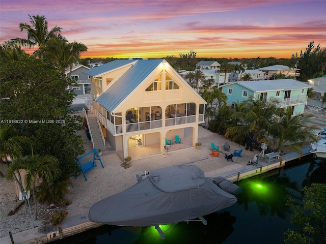 1015 Adams Dr, Key Largo, FL 33037 - back of house at dusk featuring a sunroom, a patio, metal roof, stucco siding, and stairway
