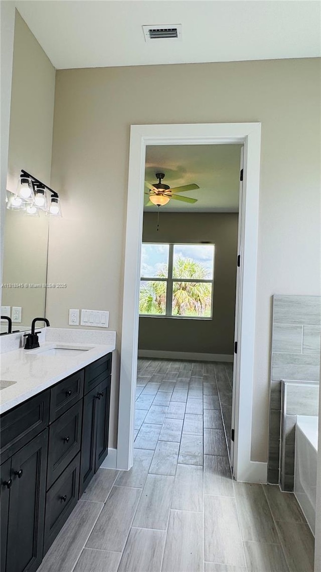 1115 Leader St, La Belle, FL 33935 - bathroom with double vanity, a bath, ceiling fan, wood tiled floors, and baseboards