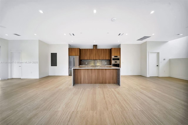 1513 SW 11th Ter, Miami, FL 33135 - kitchen featuring open floor plan, brown cabinetry, appliances with stainless steel finishes, backsplash, and light countertops