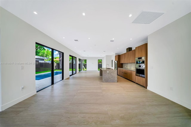 1513 SW 11th Ter, Miami, FL 33135 - kitchen featuring modern cabinets, brown cabinetry, open floor plan, a center island with sink, and light countertops