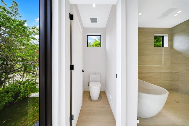 1513 SW 11th Ter, Miami, FL 33135 - bathroom with a soaking tub, toilet, and wood finished floors