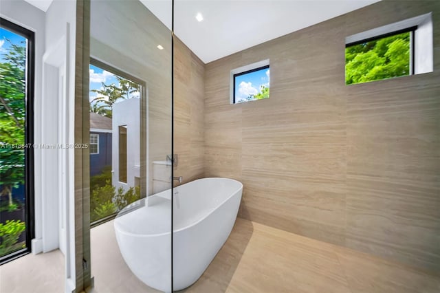1513 SW 11th Ter, Miami, FL 33135 - bathroom featuring a soaking tub, healthy amount of natural light, and tile walls
