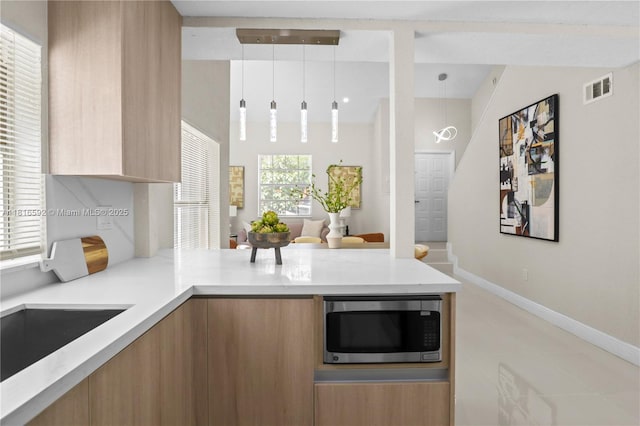 12633 NW 12th Ct, Sunrise, FL 33323 - kitchen with stainless steel microwave, modern cabinets, a peninsula, baseboards, and decorative light fixtures
