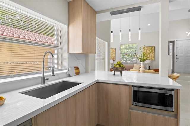 12633 NW 12th Ct, Sunrise, FL 33323 - kitchen with stainless steel microwave, a sink, modern cabinets, light stone counters, and a peninsula