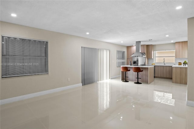 12633 NW 12th Ct, Sunrise, FL 33323 - kitchen featuring modern cabinets, range hood, light tile patterned floors, a breakfast bar area, and brown cabinets