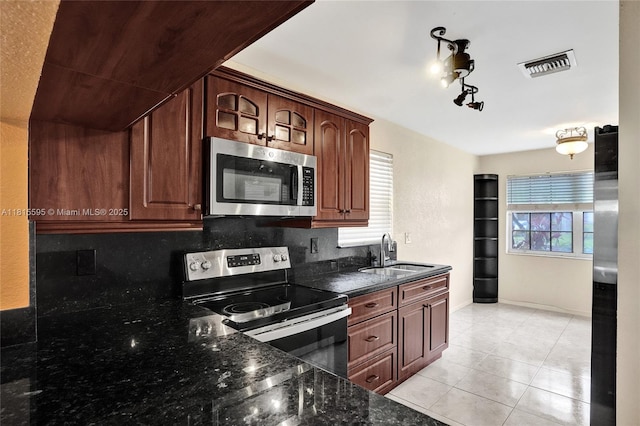 9601 NW 8th Cir, Plantation, FL 33324 - kitchen featuring appliances with stainless steel finishes, a sink, backsplash, dark stone counters, and light tile patterned floors