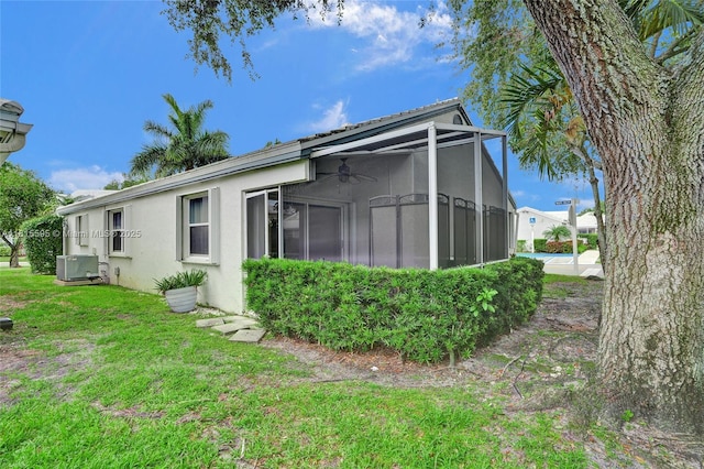 9601 NW 8th Cir, Plantation, FL 33324 - back of property with stucco siding, a ceiling fan, a yard, central AC, and a sunroom