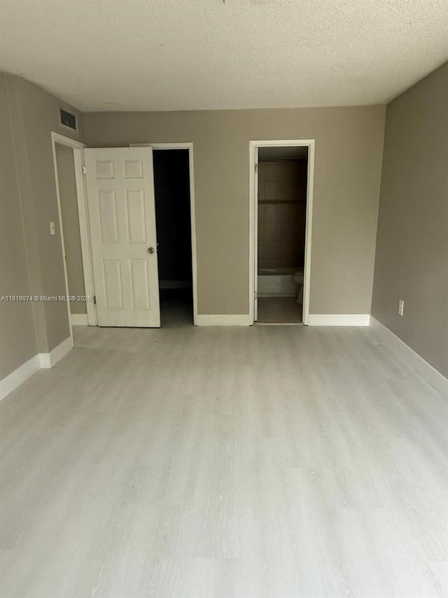 870 NW 87th Ave Unit 310, Miami, FL 33172 - unfurnished bedroom featuring light wood-style flooring, baseboards, and a textured ceiling
