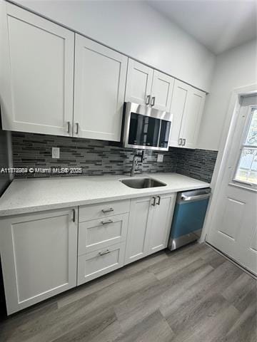 280 NE 169th St, North Miami Beach, FL 33162 - kitchen featuring appliances with stainless steel finishes, wood finished floors, white cabinets, and light countertops