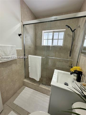 280 NE 169th St, North Miami Beach, FL 33162 - bathroom with vanity, a stall shower, tile walls, and tile patterned flooring