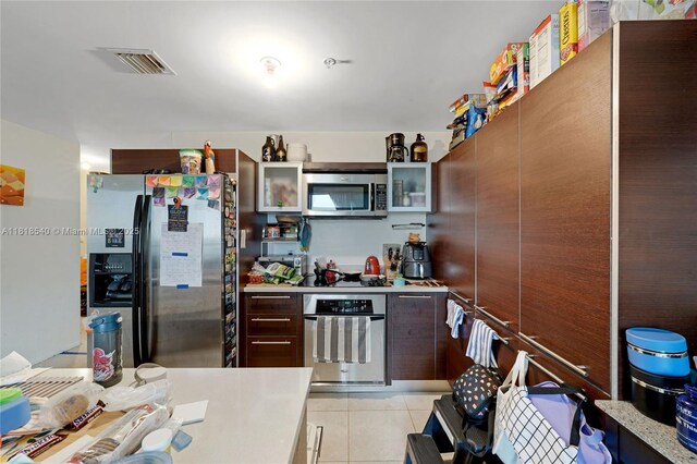 1900 N Bayshore Dr Unit 1411, Miami, FL 33132 - kitchen with appliances with stainless steel finishes, light countertops, light tile patterned floors, and glass insert cabinets