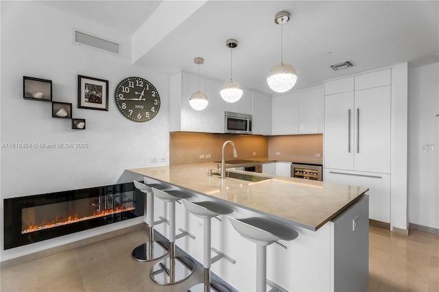 68 SE 6th St Unit 1704, Miami, FL 33131 - kitchen featuring a sink, stainless steel microwave, wine cooler, modern cabinets, and white cabinetry
