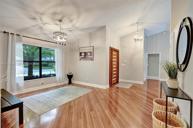 18366 Lake Bend Dr, Jupiter, FL 33458 - entrance foyer with a chandelier, a textured ceiling, light wood finished floors, and lofted ceiling